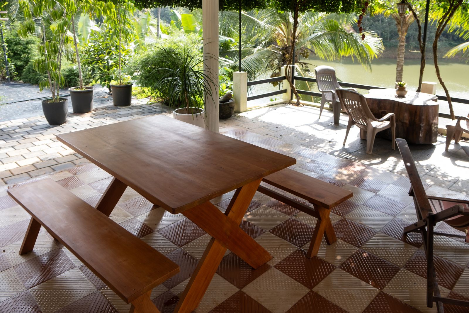 An open-air terrace with long wooden tables beside the water