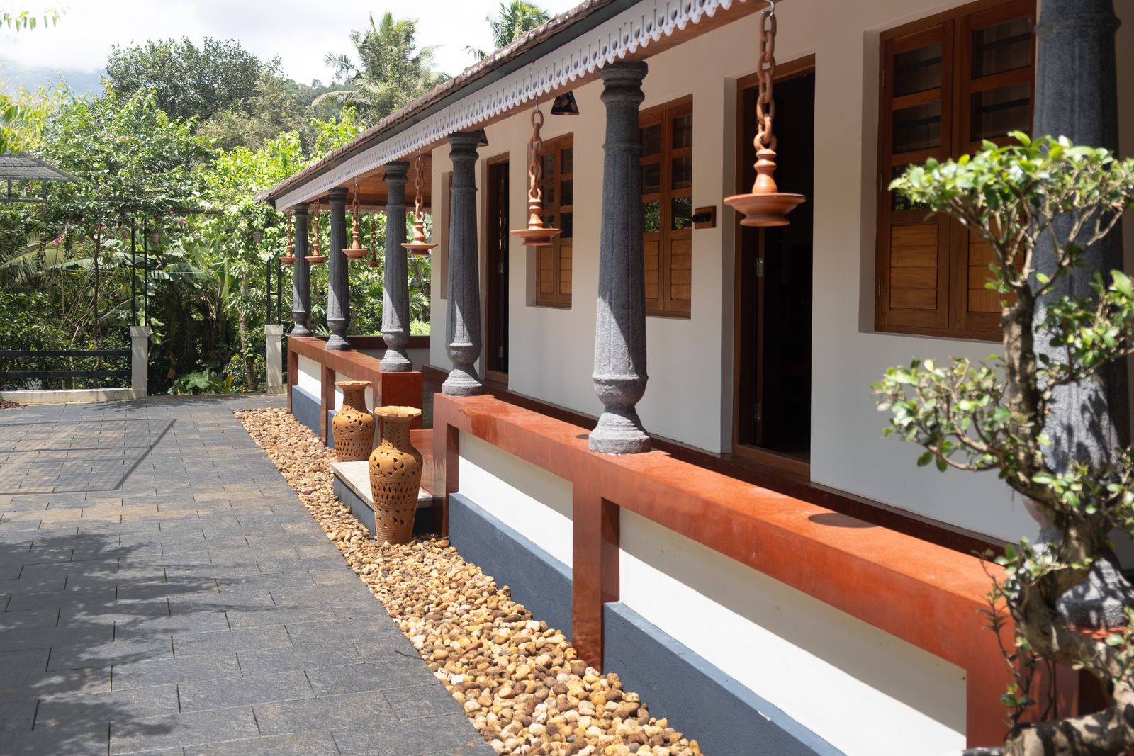 The long pillared verandah with red-oxide ledges, hanging lamps and terracotta pots